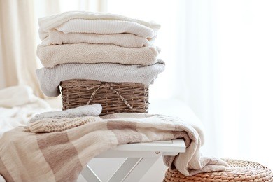 stack of cozy knitted sweaters in wicker basket