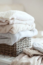 stack of cozy knitted sweaters in wicker basket