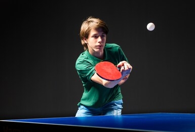 teenager play  table tennis in on black background