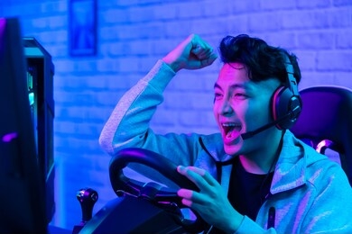 young asian pro gamer man win car racing online video game and cheer up with fist gesture