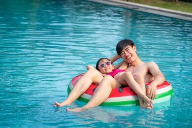 asian father  play with her daughter in a swimming pool in a tropical resort, this image can use for family, girl, summer and relax concept.