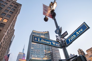 library way street sign with skyscrapers at sunset - new york city.