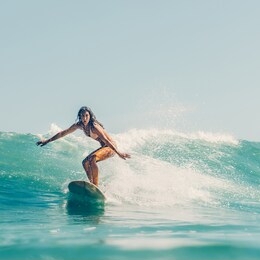 beautiful young brunette girl in a bikini swimsuit ride wave. sporty surfer woman surfing in mauritius in the indian ocean on the background of blue sky, clouds and transparent waves. outdoor active.