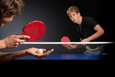 two young boys playing ping pong, focus on racket