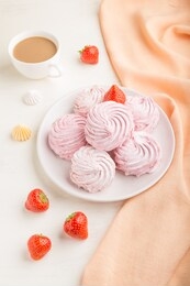 pink strawberry homemade zephyr or marshmallow with cup of coffee on white wooden background with orange textile. side view, close up.