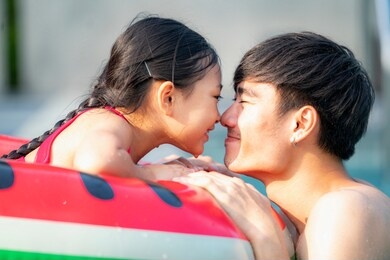 asian father  play with her daughter in a swimming pool
