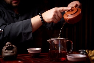tea ceremony. a young man pours tea from a teapot.