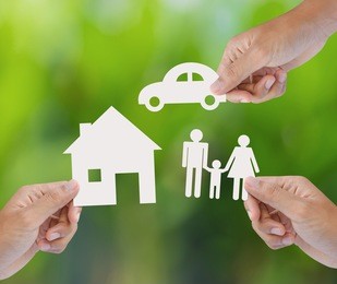 hand holding a paper home, car, family on green background, insurance concept