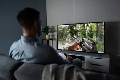 rear view of a man sitting on couch watching television