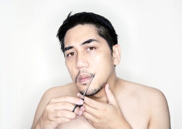 asian man cutting moustache to decor hair fashion on white background
