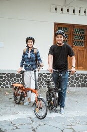 asian young couples prepare folding bikes and wear helmets before going out in front of the house