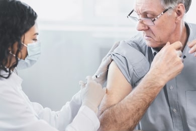 flu vaccine. close up of young latina nurse giving elderly male patient injection in hospital room, copyspace