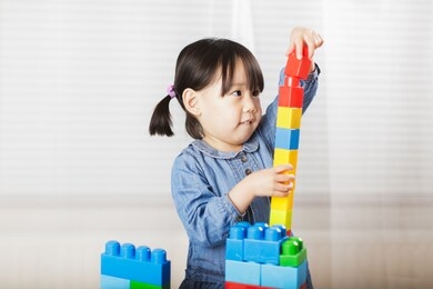 toddler girl playing creative toy blocks at home against white background