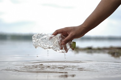 hand woman picking up empty plastic bottles cleaning on the beach. volunteer concept, environmental pollution, ecological problem.