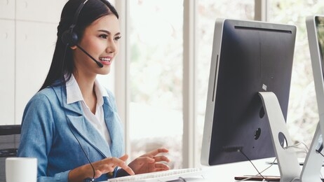 customer support agent or call center with headset works on desktop computer while supporting the customer on phone call. operator service business representative concept.