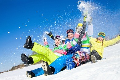 group of funny friends slide downhill together on mountain holiday
