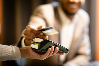 nfc technology. close up of black manager smiling, giving credit card to waitress paying with gold credit card in cafe