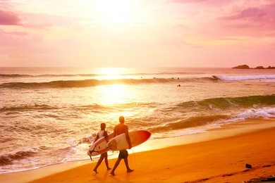 couple of surfers walks along the beach in hikkaduva - is the best surf paradise in sri lanka