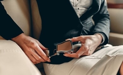 cropped image of woman fastening seat belt in aircraft. safety concept. successful young business woman working while flying in private jet.