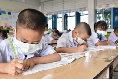 elementary school students wearing hygienic mask while studying in the classroom.