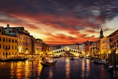 ponte rialto and gondola at sunset in venice, italy