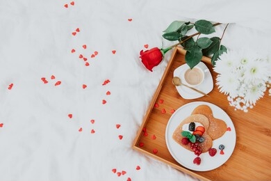 pancakes in the shape of a heart with berries, morning  coffee and rose on white bed. valentine's day breakfast concept