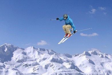 jumping skier at jump inhigh mountains at sunny day