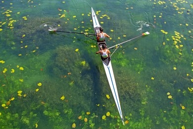 two young athletes rowing team on turquoise green lake