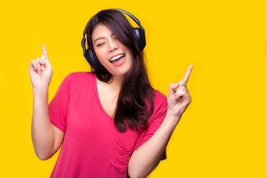 asian woman listening music, singing song with happiness, smile face. attractive beautiful young girl love sing a song and listen music that make her happy, relaxed time. yellow background, colorful