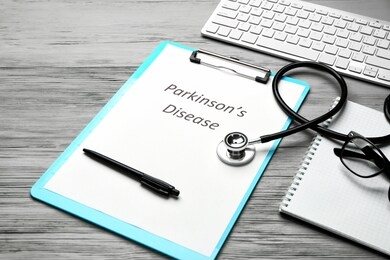 clipboard with text parkinson's disease, stethoscope and computer keyboard on wooden background
