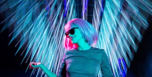 nightlife, fashion and people concept - happy young woman wearing pink wig and black sunglasses dancing at nightclub over neon ultraviolet lights background