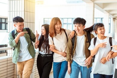 group of happy students walking along the corridor at college
