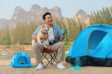 happy asian man playing with his dog in the park, camping with dog.