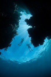a pair of snorkelers look down on a coral reef drop off near the island of misool in raja ampat, papua, indonesia. this region is known for its high marine biological diversity and great scuba diving.