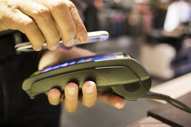 man paying with nfc technology on cell phone, in clothing store