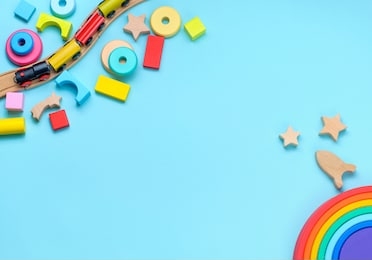 wooden toys rainbow, train and blocks on blue background with blank space for text. top view, flat lay.