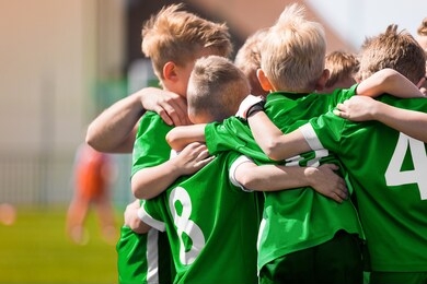 happy sports boys in a school team. kids huddling in a team on tournament competition before the final match. players gathering together in a circle to strategize and motivate 
