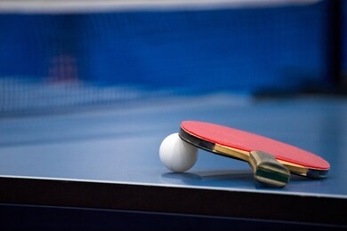rackets and ball on a blue tennis table.