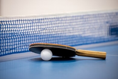 rackets and ball on a blue tennis table.