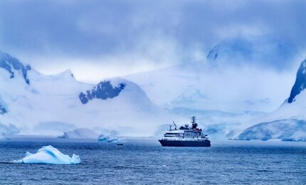tourist ship snow mountains glaciers charlotte bay antarctic peninsula antarctica.  glacier ice blue because air squeezed out of snow.