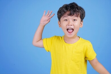 close up portrait of cute boy pointing with finger gesture, isolated on blue background