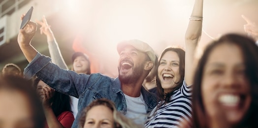 excited couple cheering  and taking selfie while at stadium. cheerful soccer fans taking selfie while watching match in stadium.