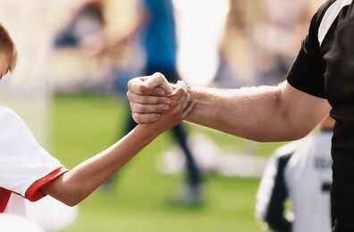 soccer football kids player and junior team coach congratulating after the match. greeting after soccer game. trainer and child shaking hands after playing tournament match