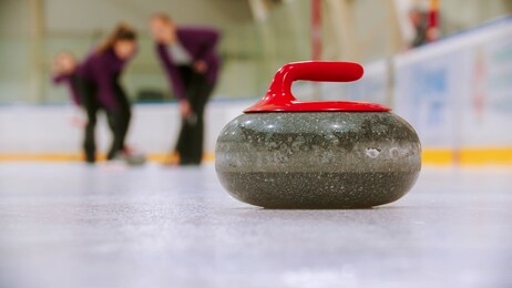 curling - a granite stone with red handle on the ice field