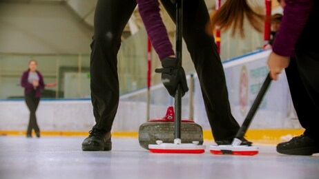 curling - leading granite stone on the ice - clearing the ice before the stone