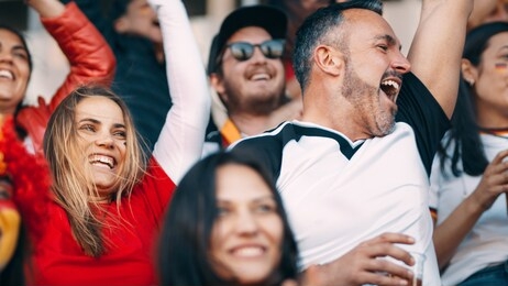 group of football fans watching a sport event and cheering. excited crowd of sports fans cheering in stadium.