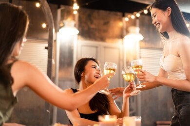 group of young asian cute women having party at rooftop restaurant. girls drinking white wine alcohol and toasting glass feeling happy enjoy, fun with smile face. night lifestyle concept.