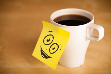drawn smiley face on a post-it note sticked on a cup