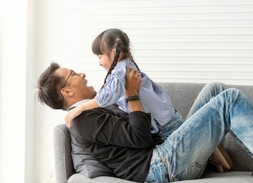 asian father and daughter playing together in living room at home.