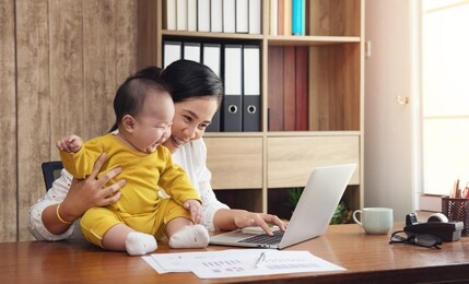 working asian mother and baby boy and laptop computer at home office. freelance and motherhood single mom internet of things network communication concept. 